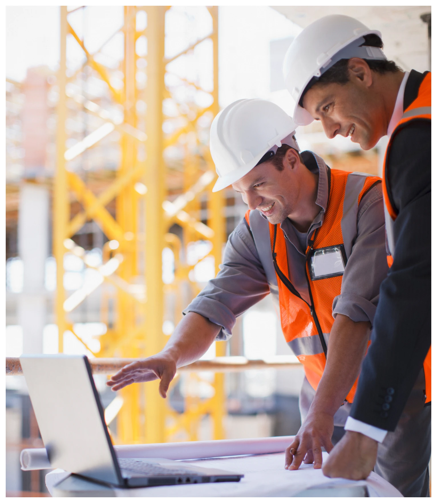 Construction workers reviewing plans on laptop